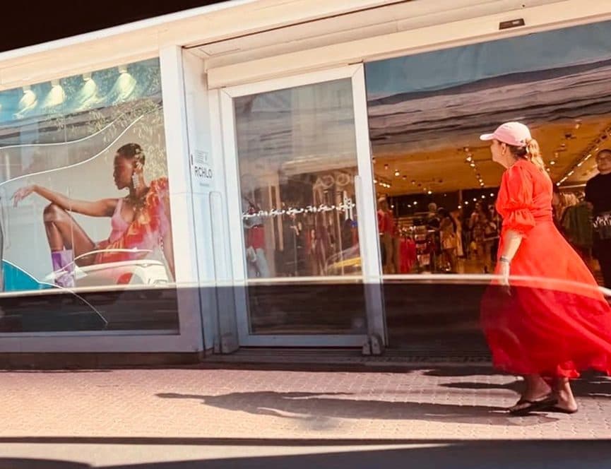 Mulher de vestido vermelho passando por vitrine